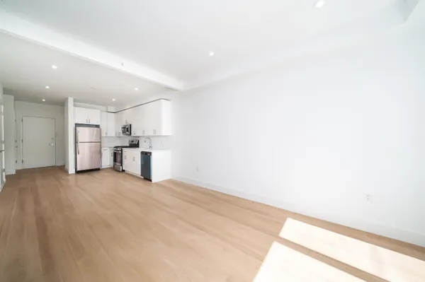 a view of empty room with kitchen