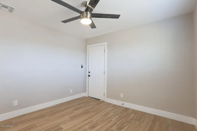 an empty room with wooden floor and a ceiling fan