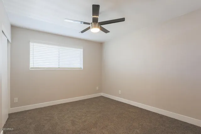 an empty room with a window and a fan