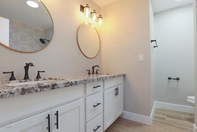 a bathroom with a granite countertop toilet sink and mirror