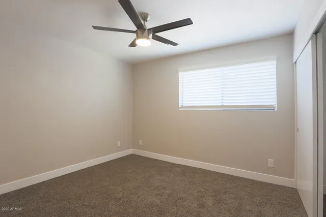 an empty room with a window and a fan