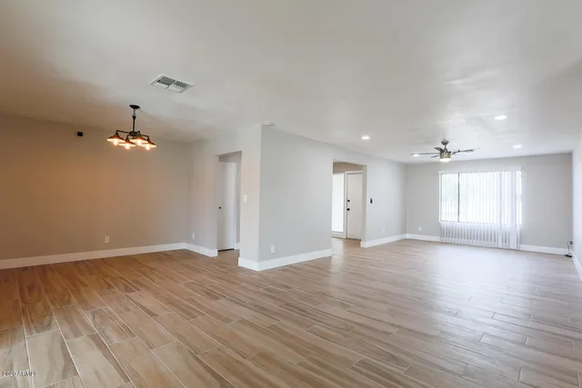 a view of an empty room with window and wooden floor