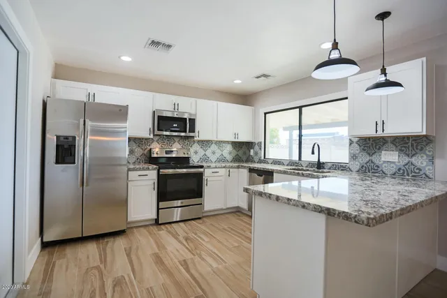 a kitchen with stainless steel appliances granite countertop a refrigerator a stove a sink and a microwave