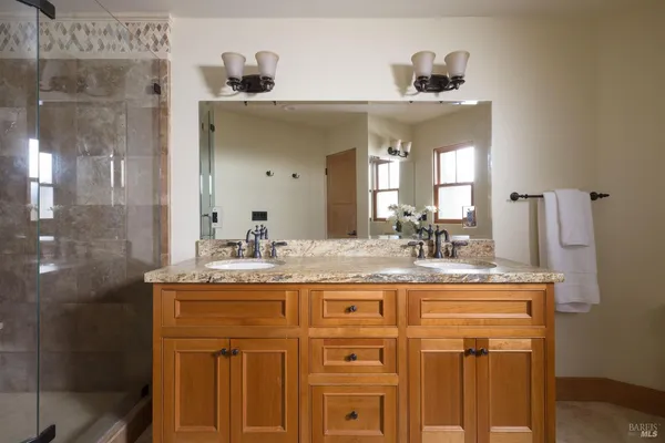 a bathroom with a granite countertop sink a mirror and shower