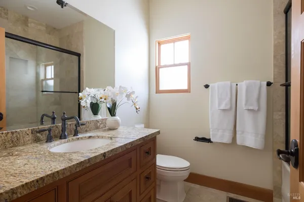 a bathroom with a granite countertop sink toilet and mirror