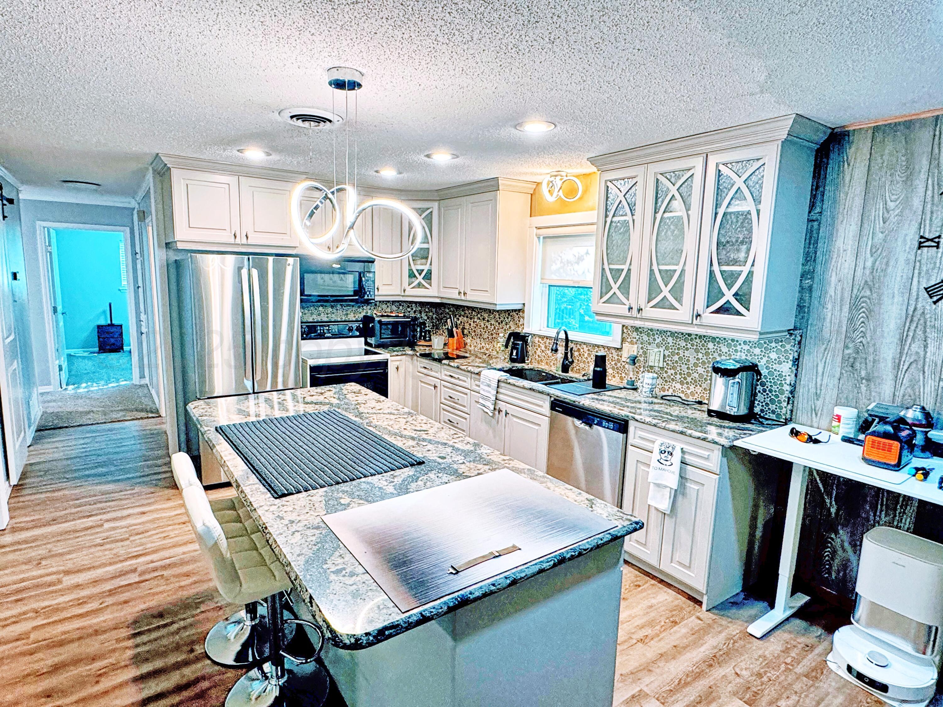 3210 South Ash Street Perryton, TX 79070 - Photo 9 of 28 a kitchen with stainless steel appliances granite countertop a refrigerator a sink dishwasher a stove and white countertops with wooden floor