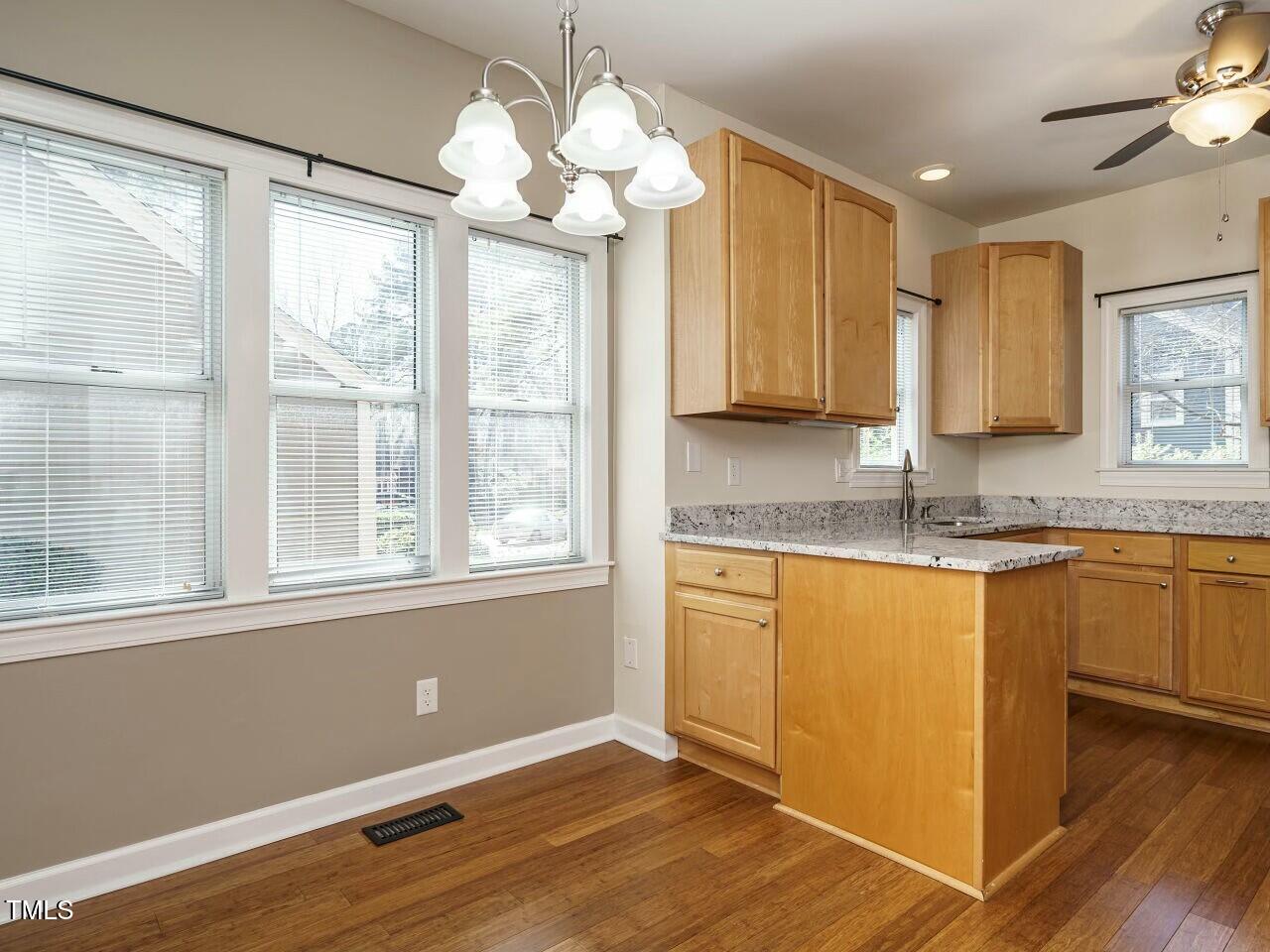 5917 Sentinel Drive Raleigh, NC 27609 - Photo 13 of 32 a kitchen with granite countertop wooden cabinets a sink and dishwasher with wooden floor