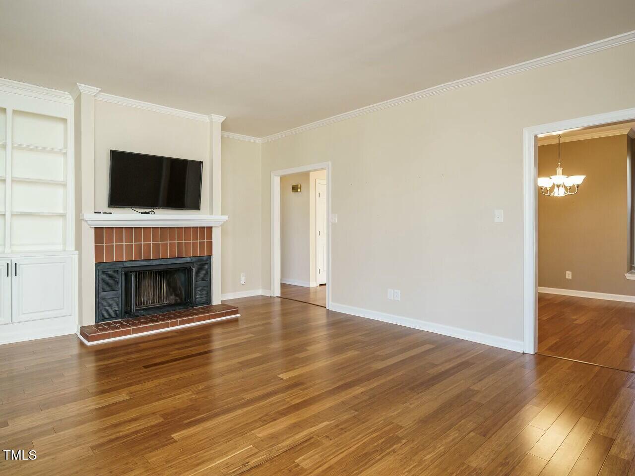 5917 Sentinel Drive Raleigh, NC 27609 - Photo 9 of 32 a view of an empty room with wooden floor fireplace and a window