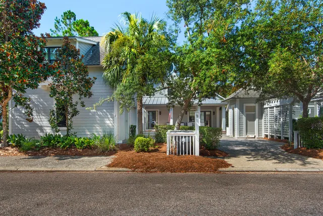 a view of a house with potted plants and a bench in front of it