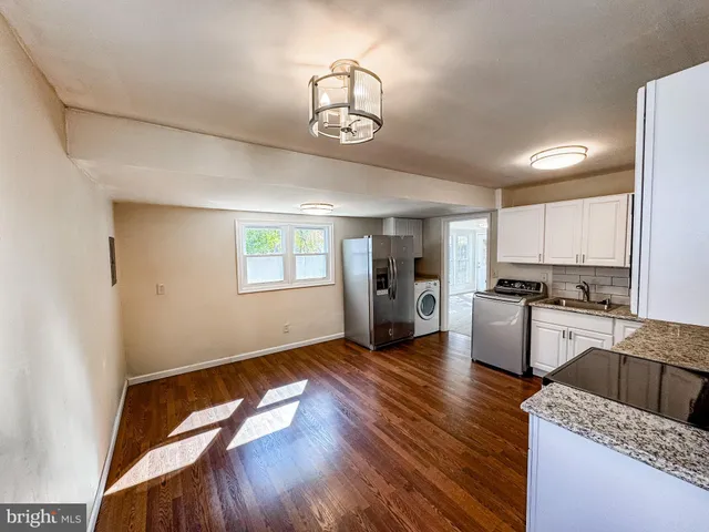 a kitchen with granite countertop a stove a sink dishwasher a refrigerator and wooden floor