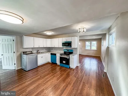 a large kitchen with a center island and wooden floor