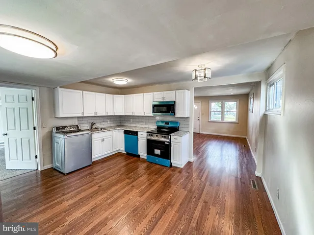 a large kitchen with a center island and wooden floor