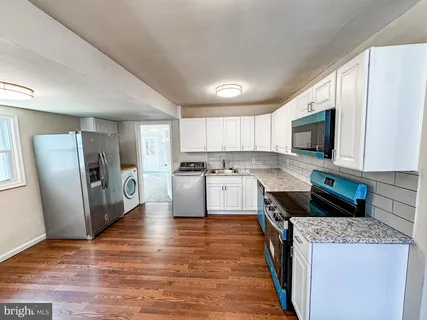 a kitchen with stainless steel appliances white cabinets a sink a stove a refrigerator and a microwave