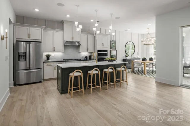 a kitchen with stainless steel appliances granite countertop a table chairs refrigerator and sink