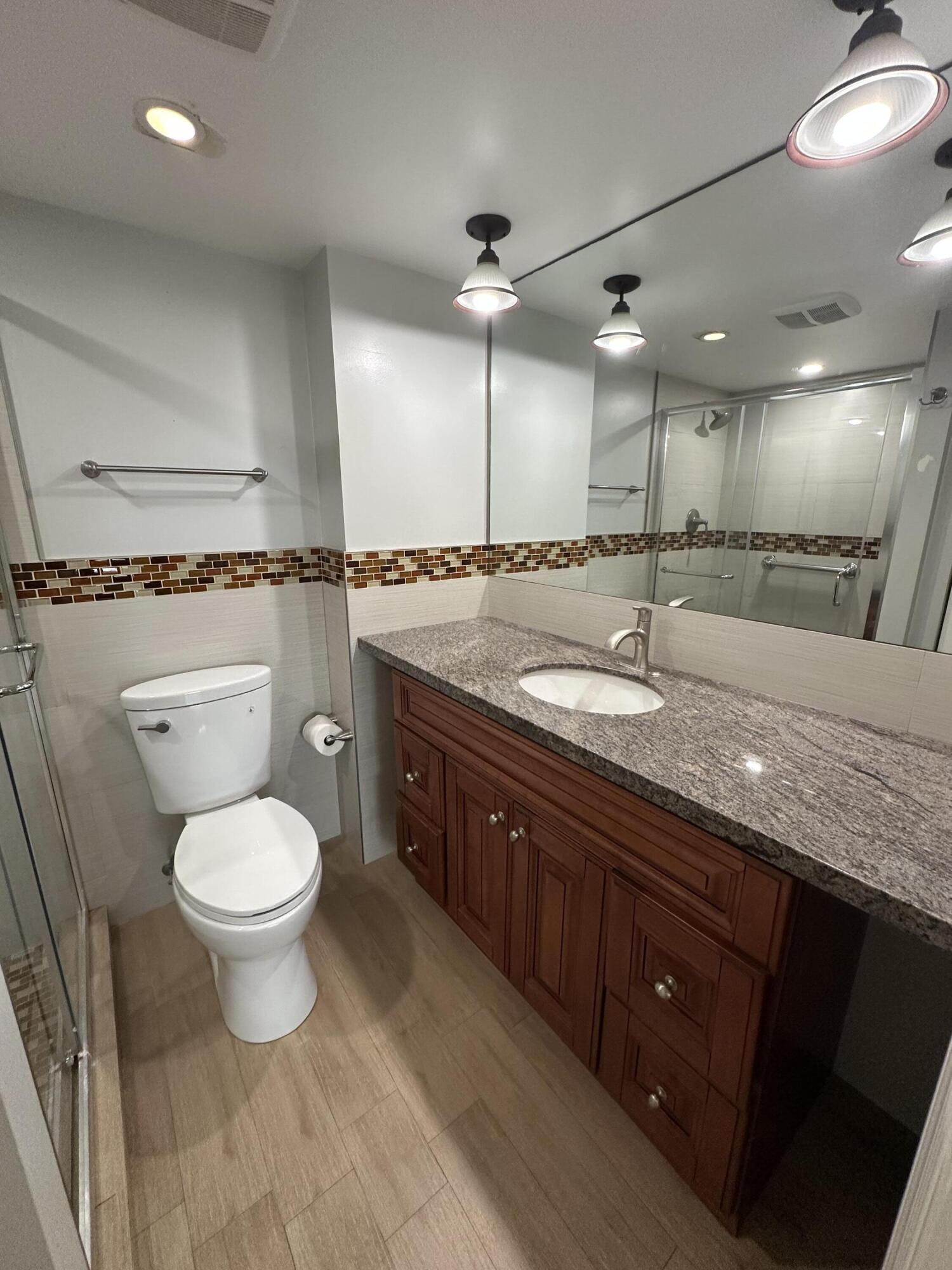 3224 South Ocean Boulevard, Unit 310B Highland Beach, FL 33487 - Photo 12 of 26 a bathroom with a granite countertop sink a toilet and a mirror
