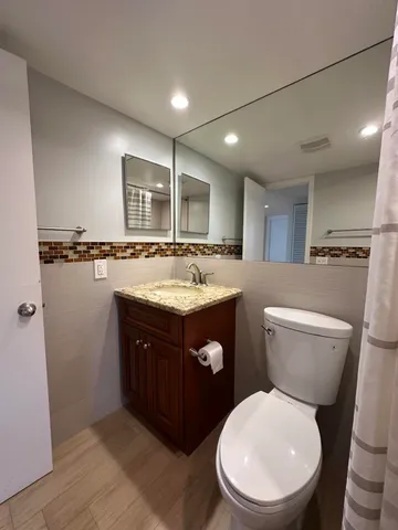a bathroom with a granite countertop toilet sink and mirror