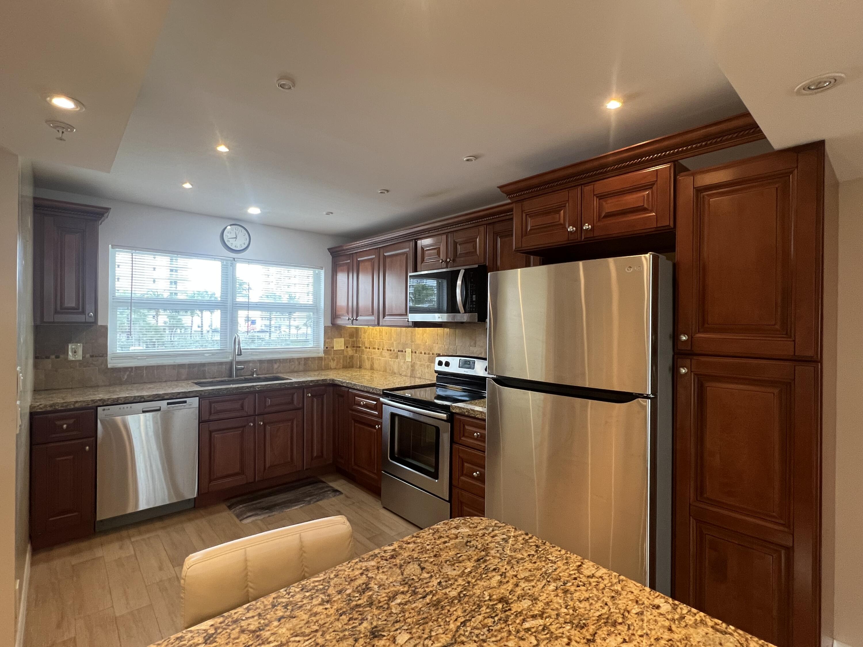 3224 South Ocean Boulevard, Unit 310B Highland Beach, FL 33487 - Photo 3 of 26 a kitchen with stainless steel appliances granite countertop a refrigerator a sink dishwasher a stove with white cabinets and wooden floor