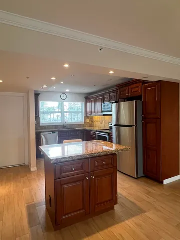 a kitchen with stainless steel appliances granite countertop a stove a refrigerator and a wooden cabinets