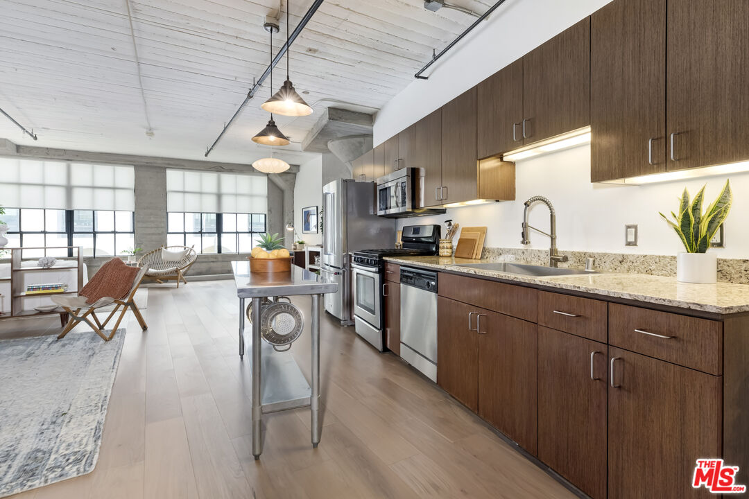 200 North San Fernando Road, Unit 208 Los Angeles, CA 90031 - Photo 11 of 37 a kitchen with stainless steel appliances granite countertop a stove a sink dishwasher a dining table and chairs with wooden floor