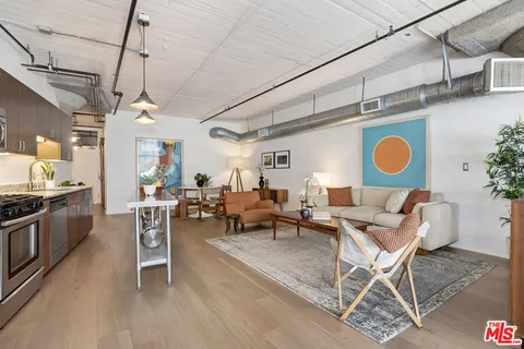 a living room with couches a dining table and chairs with wooden floor