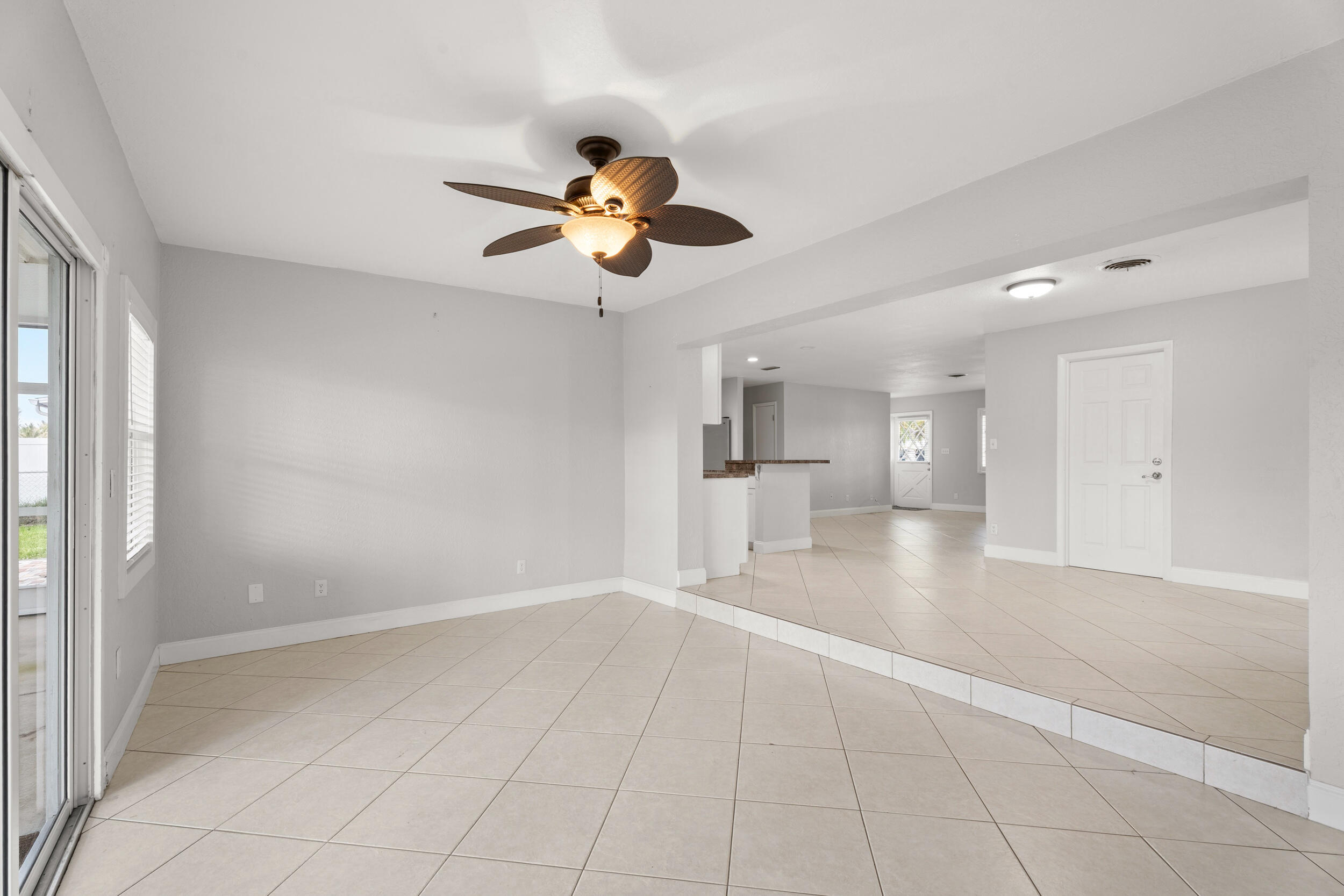 1459 Southwest Seahawk Way Palm City, FL 34990 - Photo 3 of 43 a view of an empty room with a chandelier fan and a kitchen view
