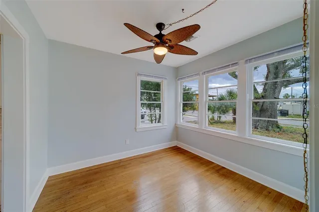an empty room with ceiling fan and windows