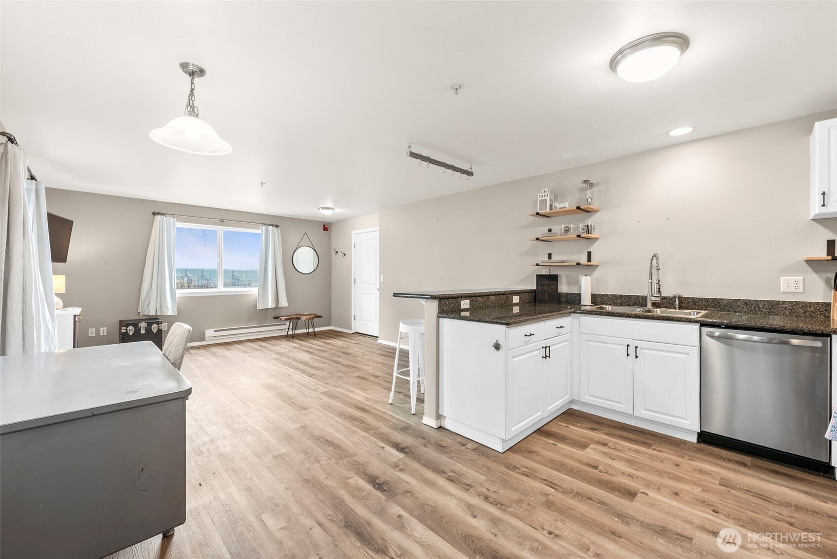 218 Broadway, Unit 5 Tacoma, WA 98402 - Photo 12 of 32 a large white kitchen with a white countertops a stove a couch and a dining table with wooden floor
