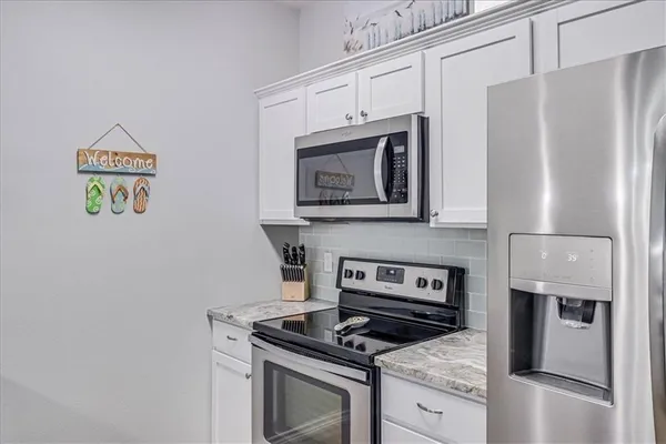 a kitchen with stainless steel appliances granite countertop a stove a refrigerator and a microwave