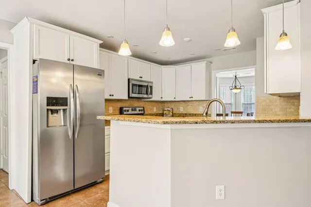 a kitchen with stainless steel appliances granite countertop a refrigerator a sink and white cabinets