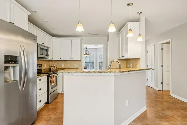 a kitchen with stainless steel appliances granite countertop a refrigerator a sink a stove and oven