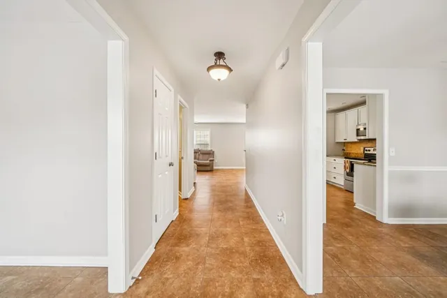a view of a hallway with wooden floor and a living room