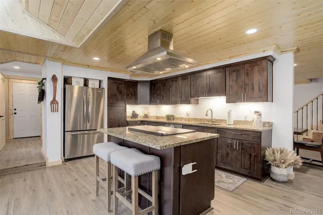 a kitchen with stainless steel appliances granite countertop a table chairs refrigerator and microwave