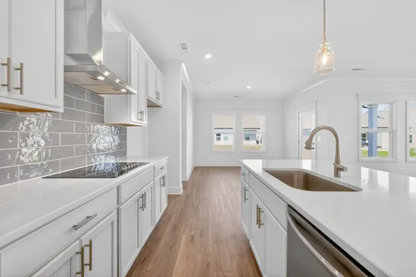 a kitchen with white cabinets a sink dishwasher and a stove with wooden floor