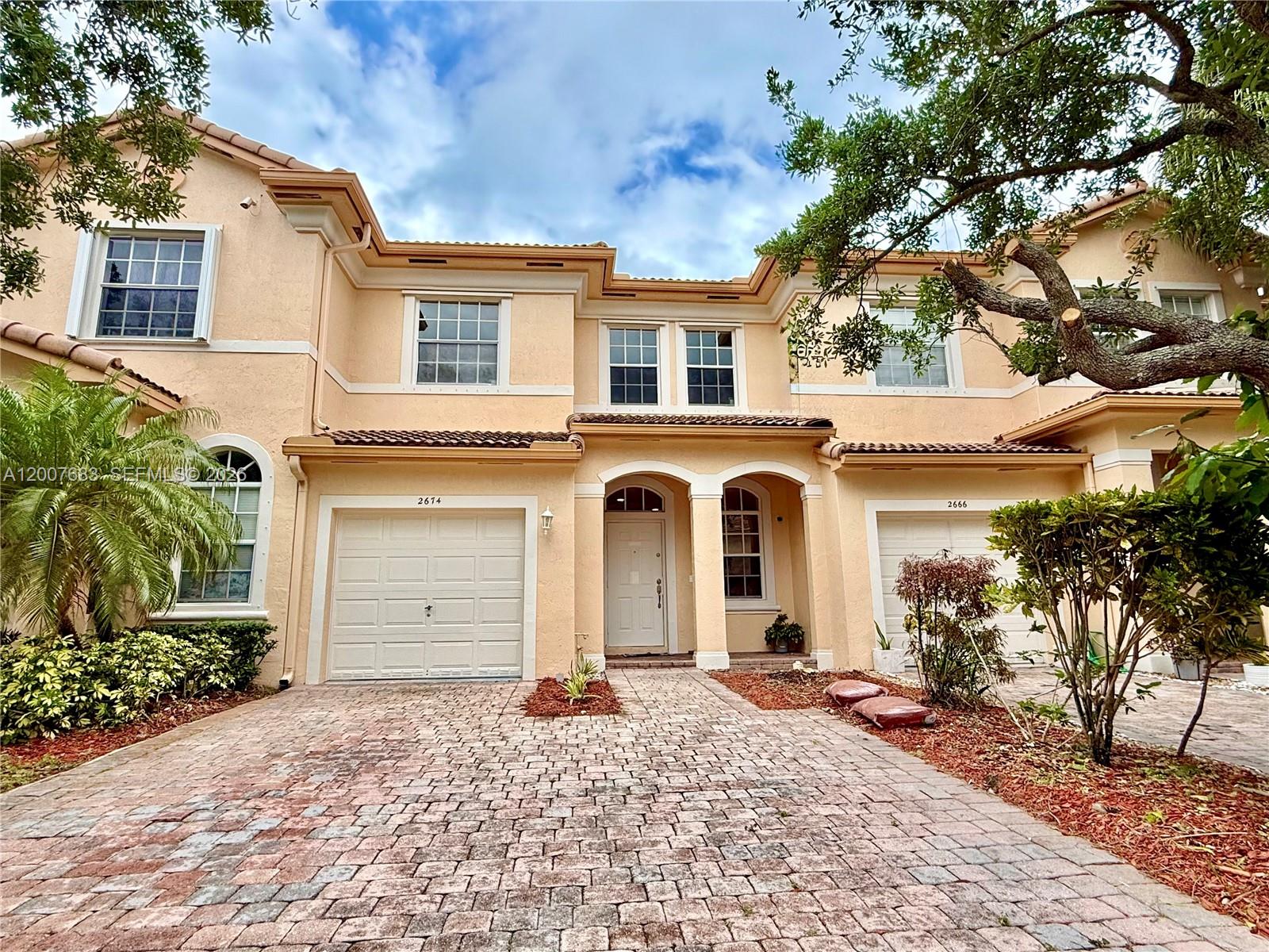 2674 Southwest 84th Terrace, Unit 102 Miramar, FL 33025 - Photo 1 of 57 a front view of a house with a yard and garage