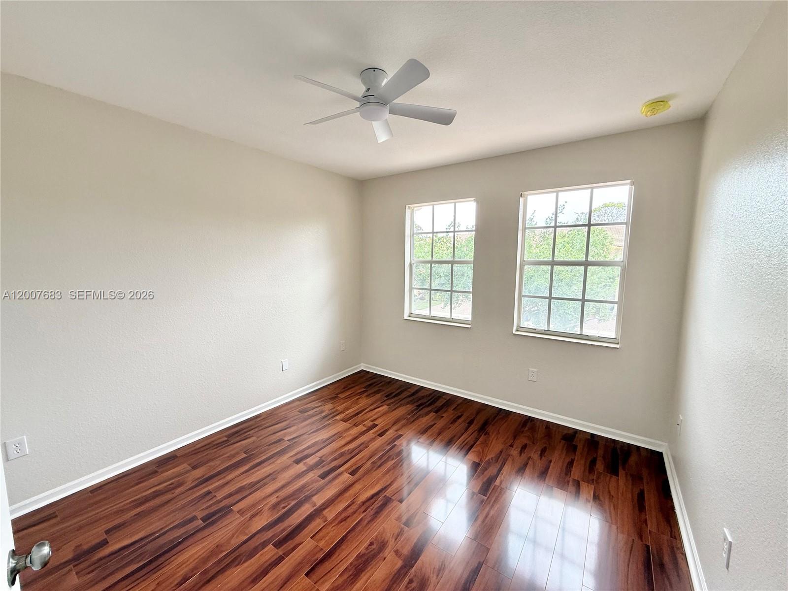 2674 Southwest 84th Terrace, Unit 102 Miramar, FL 33025 - Photo 22 of 57 an empty room with wooden floor chandelier fan and windows
