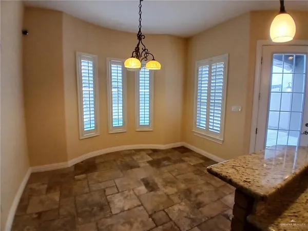 a view of an empty room with window and chandelier