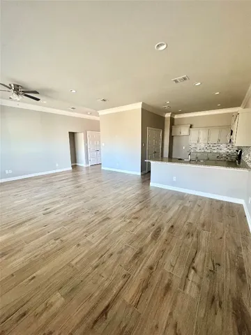 an empty room with wooden floor fan and windows
