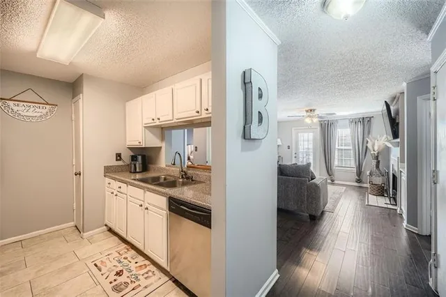 a kitchen with stainless steel appliances granite countertop a refrigerator a sink dishwasher a stove and white countertops with wooden floor