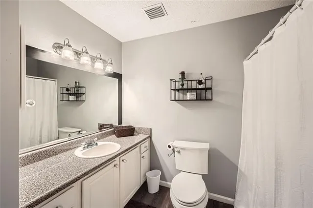 a bathroom with a granite countertop sink mirror and toilet
