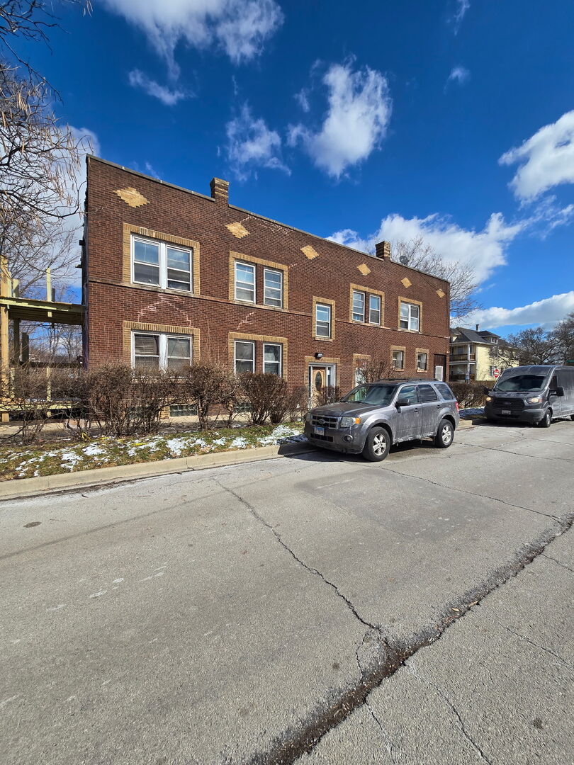 a buildings with car parked on the side of road