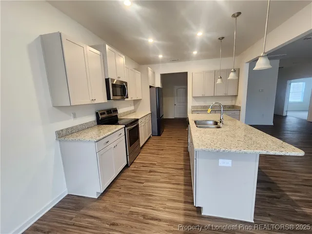 a large kitchen with stainless steel appliances kitchen island a large counter top a sink a stove and a refrigerator