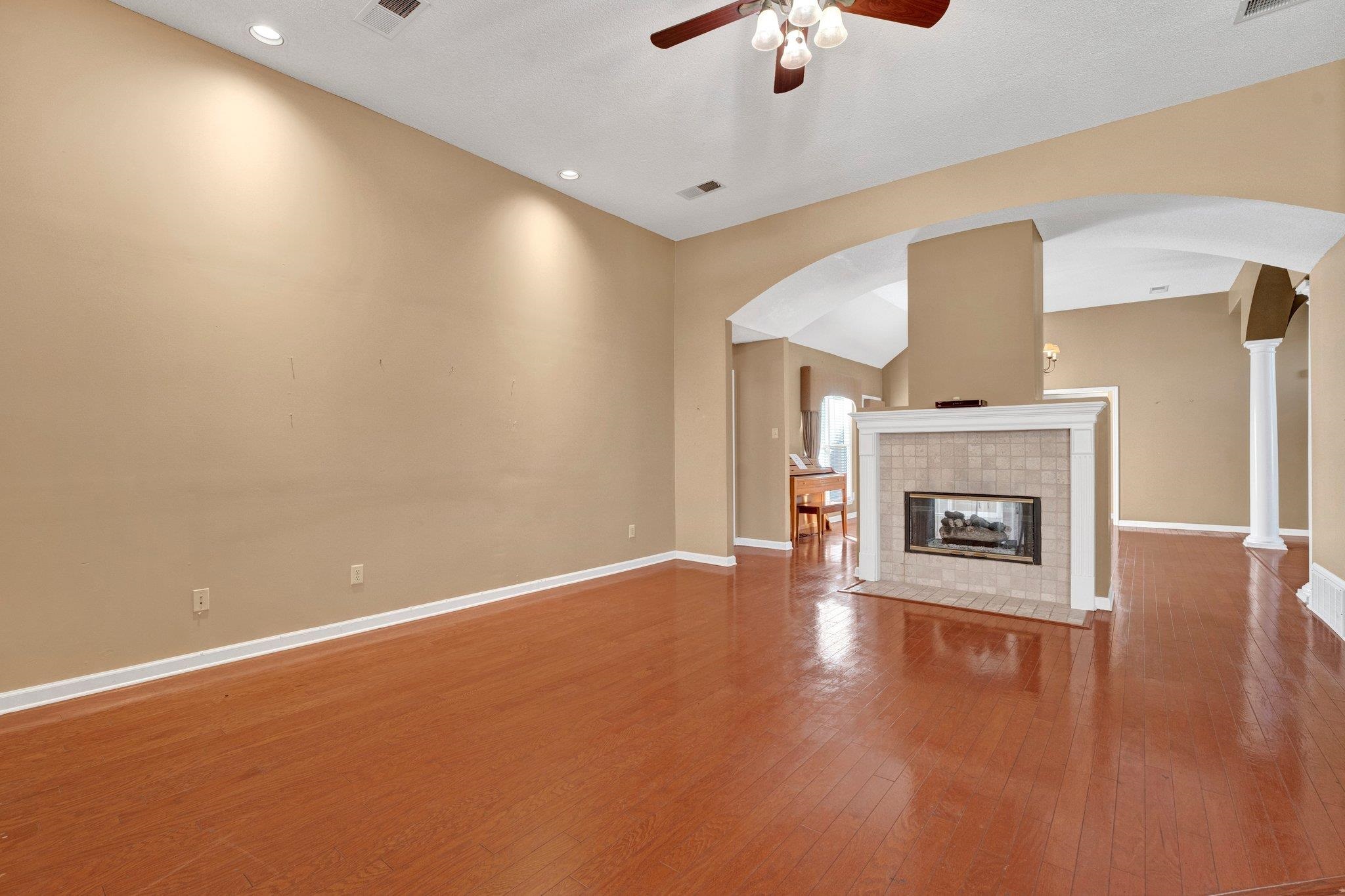 6150 Ricks Road Arlington, TN 38002 - Photo 22 of 40 Unfurnished living room with wood-type flooring, vaulted ceiling, ceiling fan, and a tiled fireplace