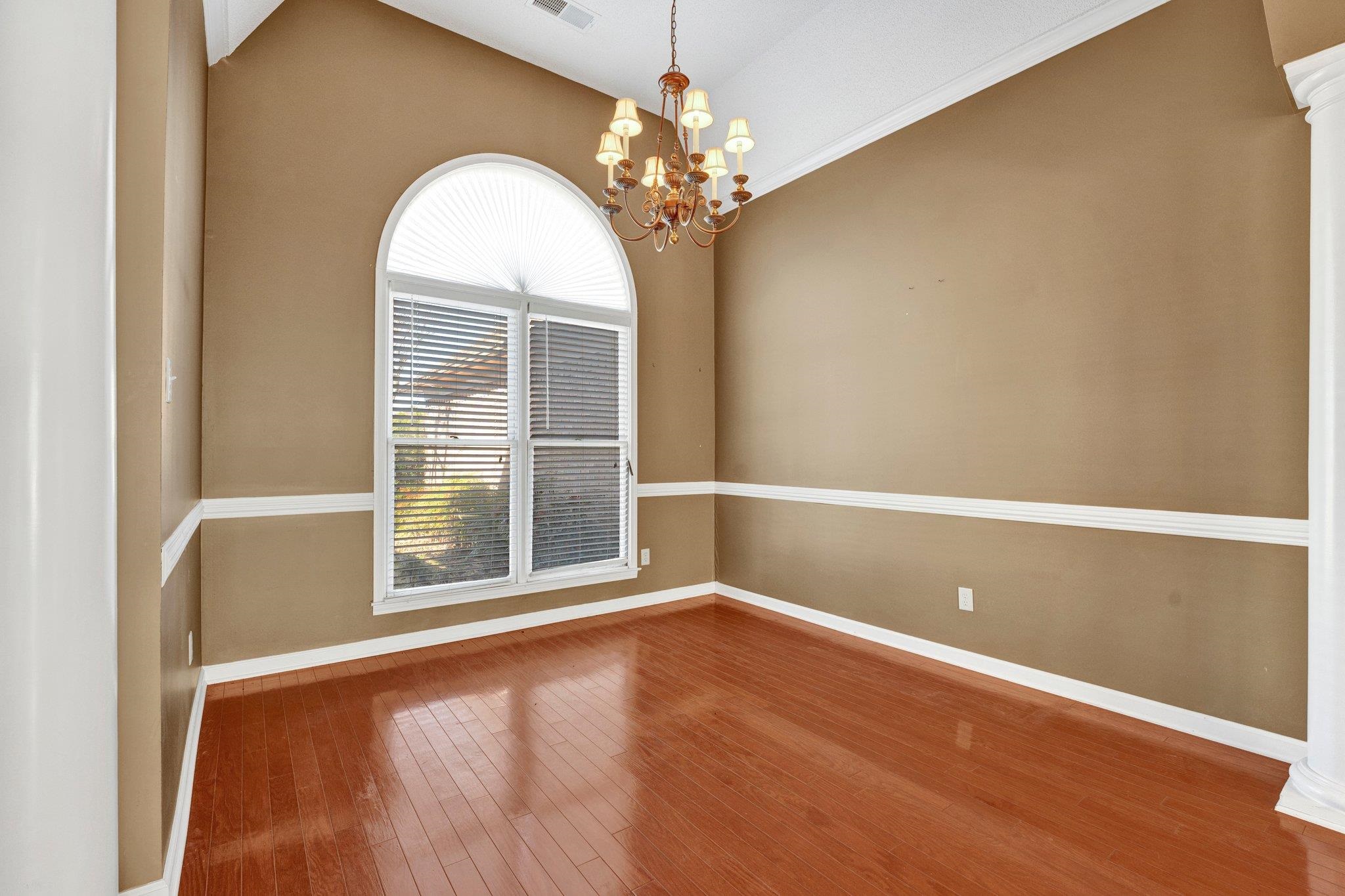 6150 Ricks Road Arlington, TN 38002 - Photo 27 of 40 Unfurnished room featuring ornate columns, crown molding, a notable chandelier, hardwood / wood-style floors, and lofted ceiling