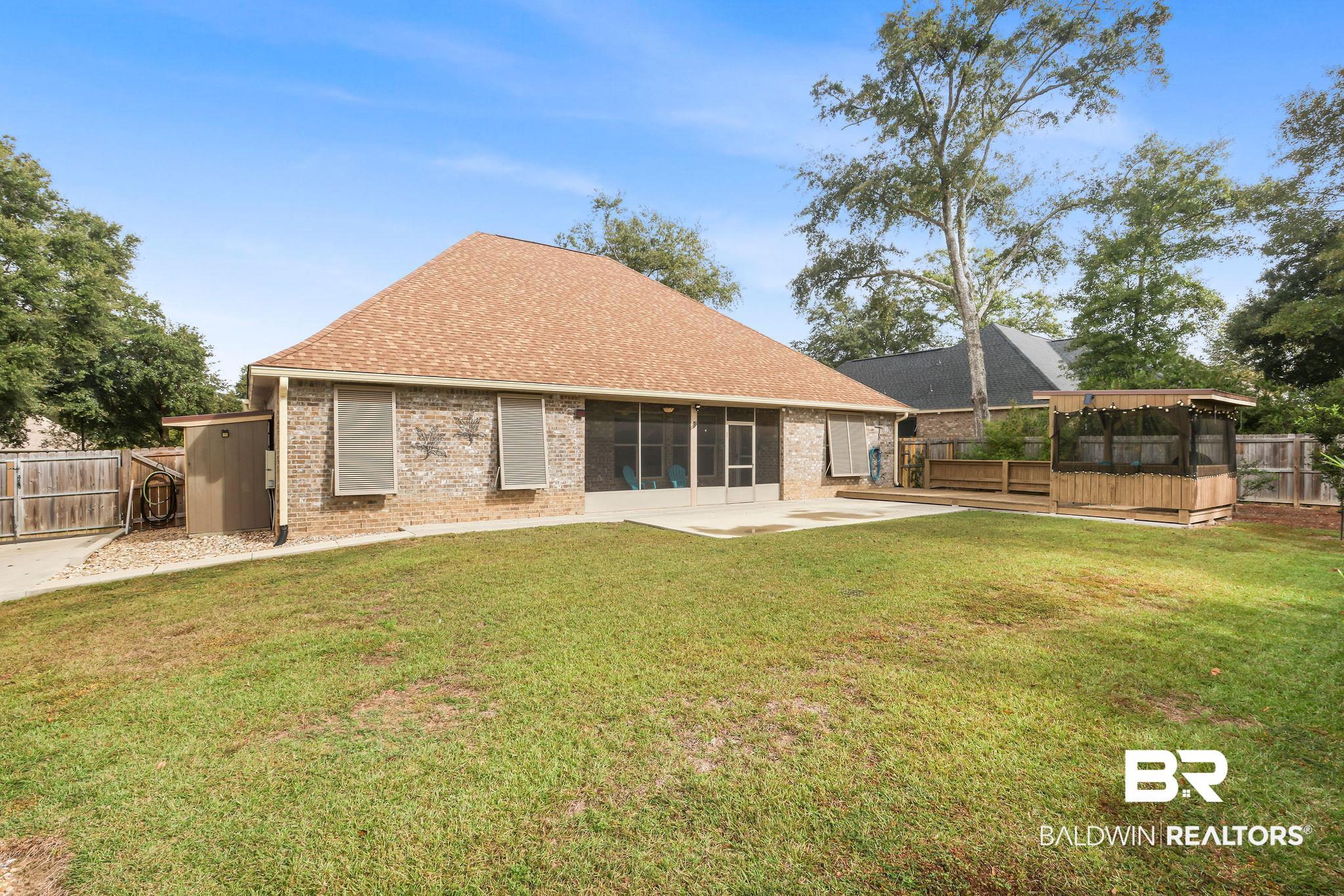 1086 Destin Avenue Foley, AL 36535 - Photo 23 of 30 Rear view of property featuring a sunroom, a patio area, a lawn, and a storage shed