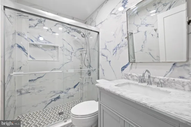 a bathroom with a granite countertop sink a toilet and shower