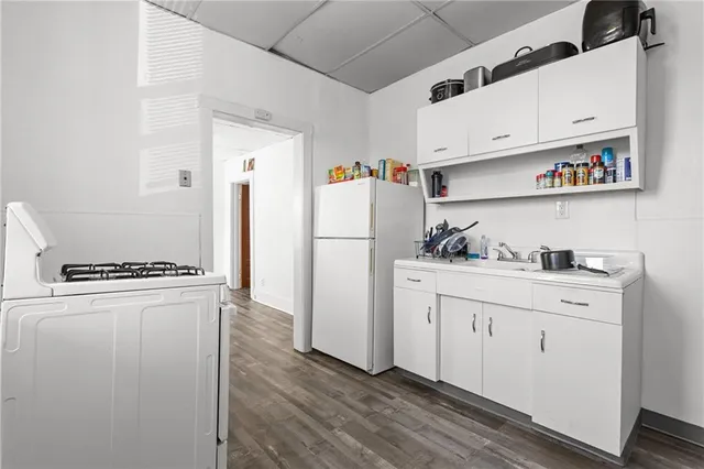 a kitchen with stainless steel appliances a refrigerator a sink and white cabinets