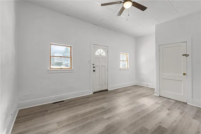 a view of an empty room with a window and wooden floor