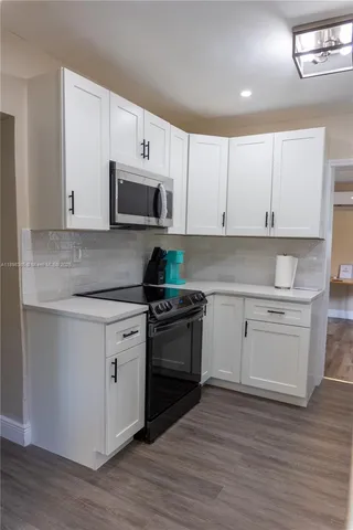 a kitchen with granite countertop white cabinets and stainless steel appliances