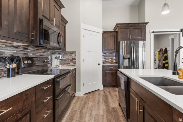 463 South Trejo Ridge Road Grantsville, UT 84029 - Photo 7 of 22 Modern kitchen featuring dark wood cabinetry, stainless steel appliances, a multi-tone glass tile backsplash, white countertops, and wood-finish flooring