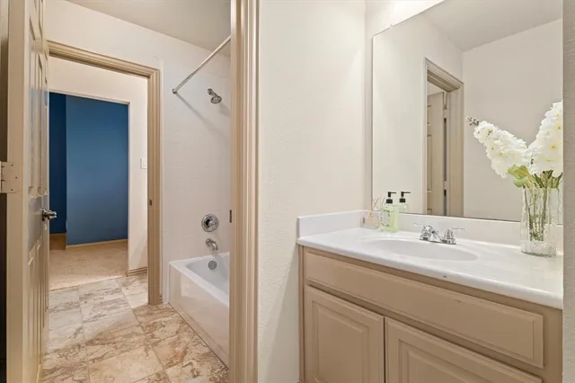 a en suite bathroom with a granite countertop sink and a mirror a bathtub
